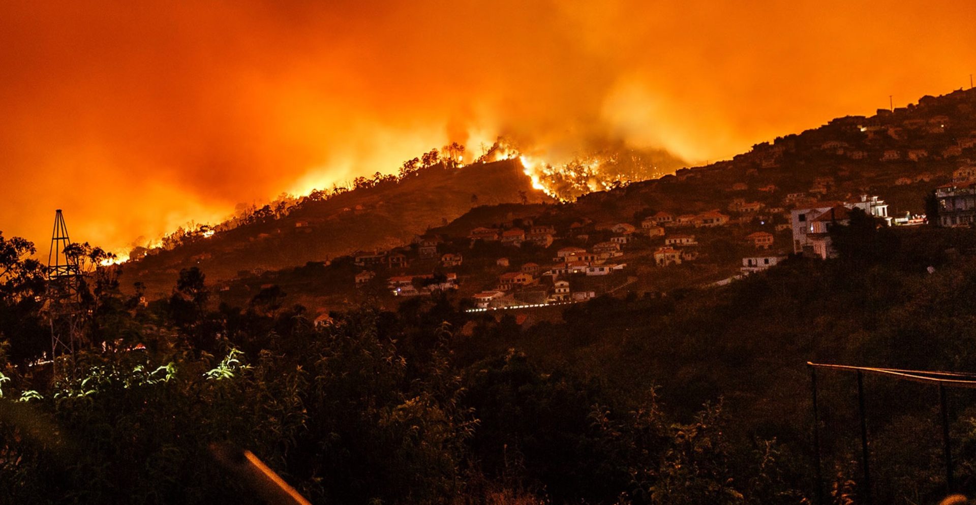 Photograph of a mountain wildfire consuming homes